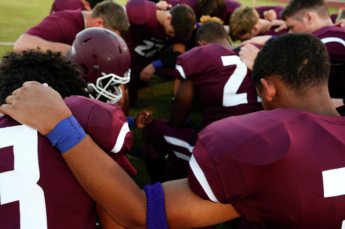 Silsbee junior varsity football players bow their heads in prayer before their game on Thursday evening. The players wore purple sweatbands and wrist tape in memory of JV cheerleader Tristan Dilley, whose favorite color was purple. Dilley was killed on Sunday. Photo taken Thursday 10/5/17 Ryan Pelham/The Enterprise