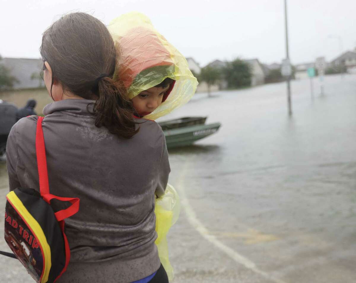 A woman and child, who declined to be identified,﻿ are rescued from rising flood waters in a neighborhood along Beechnut Road, south of the Barker Reservoir, in Fort Bend County as heavy rains from ﻿Harvey continued flooding their street.﻿