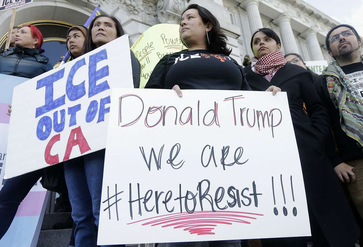 In this Jan. 25, 2017 file photo protesters hold signs as they listen to speakers at a rally outside of City Hall in San Francisco, Calif. California Gov. Jerry Brown signed legislation, SB54, the statuary state bill, that extends protections statewide for immigrants living the United State illegally, Thursday, Oct. 5, 2017. (AP Photo/Jeff Chiu,file)