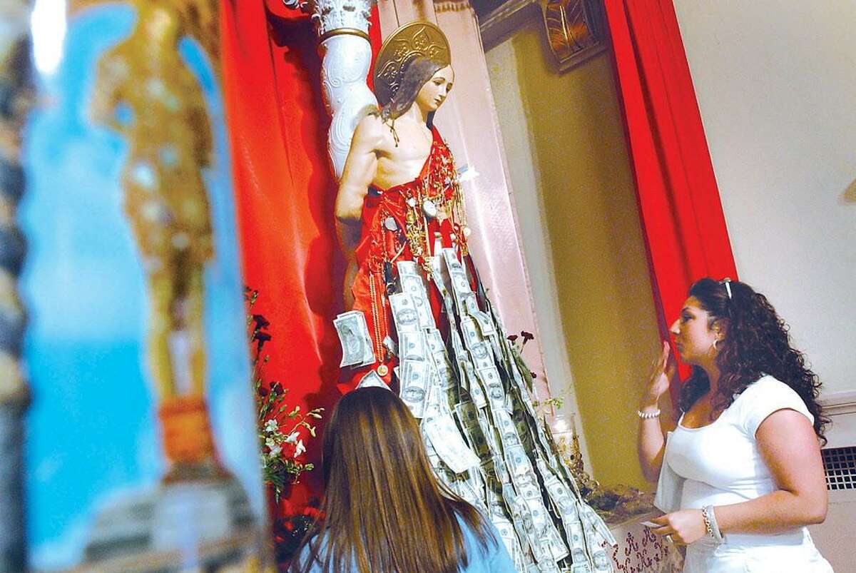A woman honors a statue of St. Sebastian during the annual feast at Middletown’s St. Sebastian Church in this archive photograph. In Melilli, Sicily, Middletown's sister city, the patron saint has been celebrated for more than 600 years. Many generations of residents immigrated to Middletown from the Italian island beginning in the 1890s.