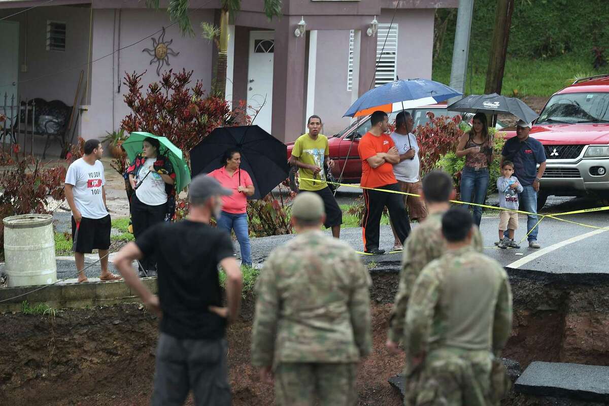 BARRANQUITAS, PUERTO RICO - OCTOBER 07: People look on as U.S. Army 1st Special Force Command soldiers check for people in need as heavy rains fall on the area days after Hurricane Maria swept through the island on October 7, 2017 in Barranquitas, Puerto Rico. The team of soldiers are delivering supplies to people as well as checking on the well being of people caught up in the natural disaster. (Photo by Joe Raedle/Getty Images)