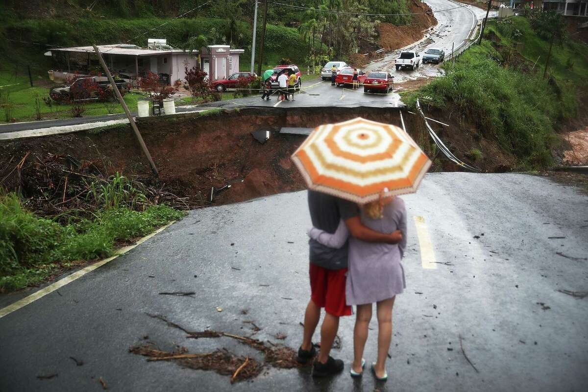BARRANQUITAS, PUERTO RICO - OCTOBER 07: People look on at a section of a road that collapsed and continues to erode days after Hurricane Maria swept through the island on October 7, 2017 in Barranquitas, Puerto Rico. Puerto Rico experienced widespread damage including most of the electrical, gas and water grid as well as agriculture after Hurricane Maria, a category 4 hurricane, passed through. (Photo by Joe Raedle/Getty Images) *** BESTPIX ***