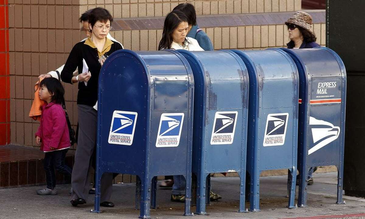 People deposit mail in the mailboxes in front of the Chinatown Post Office on the corner of Clay and Stockton Streets on Friday August 12, 2011, in San Francisco, Ca. The demise of the blue mailboxes another casualty of the internet.