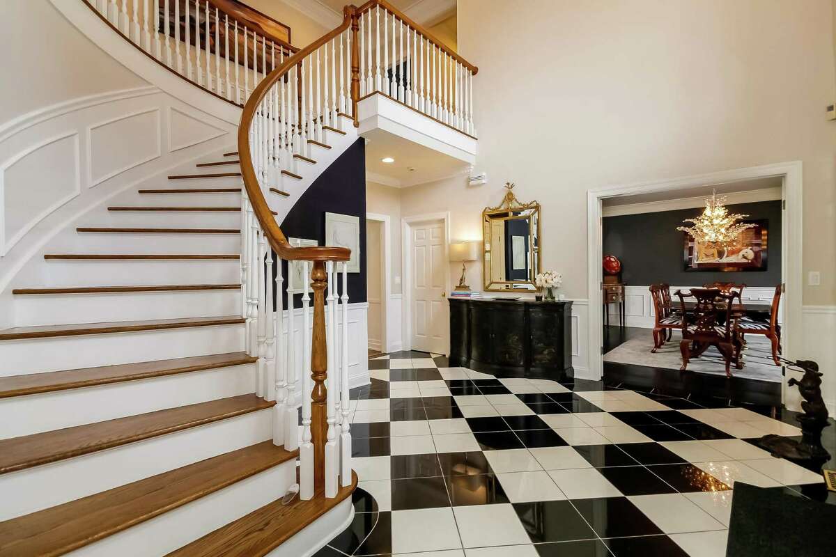 In the two-story entry foyer the flooring comprises black granite and white Glassos quartzite tile.