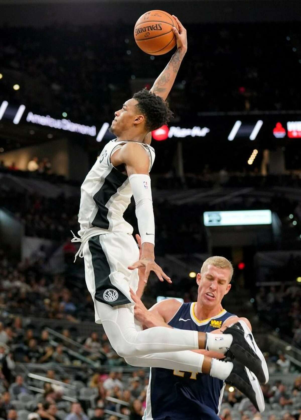 San Antonio Spurs' Dejounte Murray, left, dunks over Denver Nuggets' Mason Plumlee during the second half of a preseason NBA basketball game, Sunday, Oct. 8, 2017, in San Antonio.