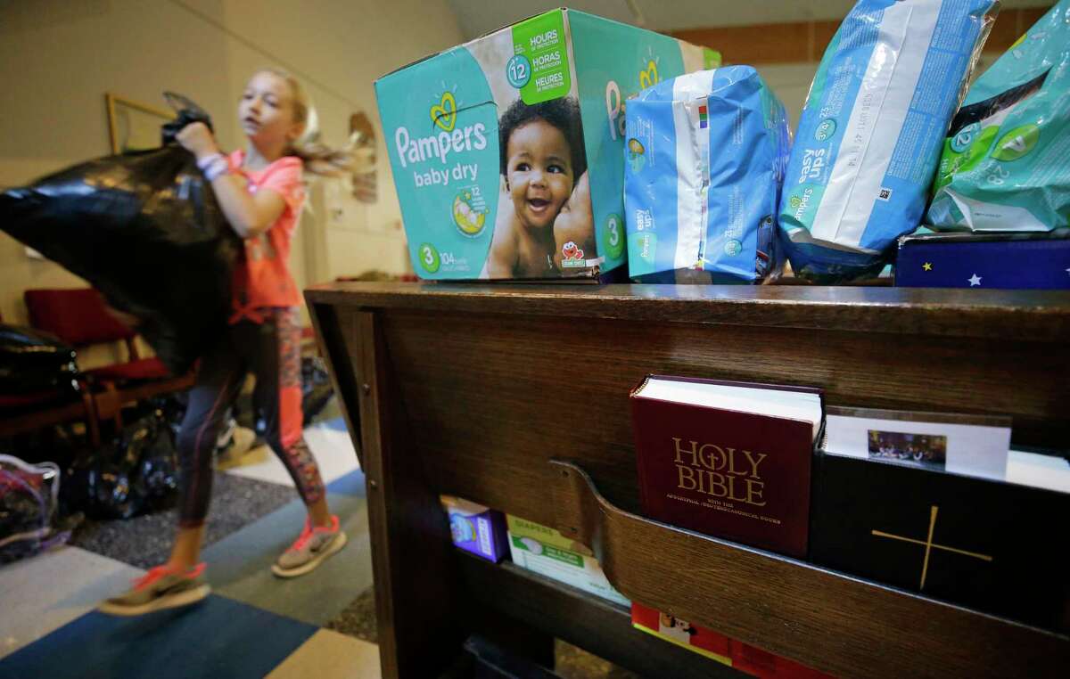 Mackenzie Breeding, 9, of Tomball carries a bag of clothing past pews filled with diapers, as volunteers organize donations at St. Mary's Episcopal Church, 15415 N. Eldridge, Wednesday, August 30, 2017 in Cypress. More than 120 people were temporarily sheltered at the church during flooding. There is an outpouring of donations after Hurricane Harvey. ( Melissa Phillip / Houston Chronicle)