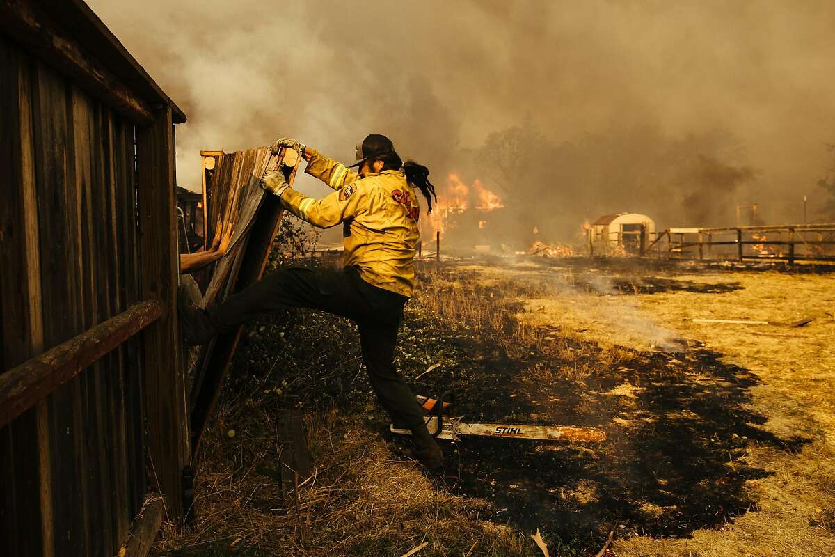 Firefighters knocks down the fence on Baird Road in Santa Rosa, Calif. Monday, October 9, 2017.