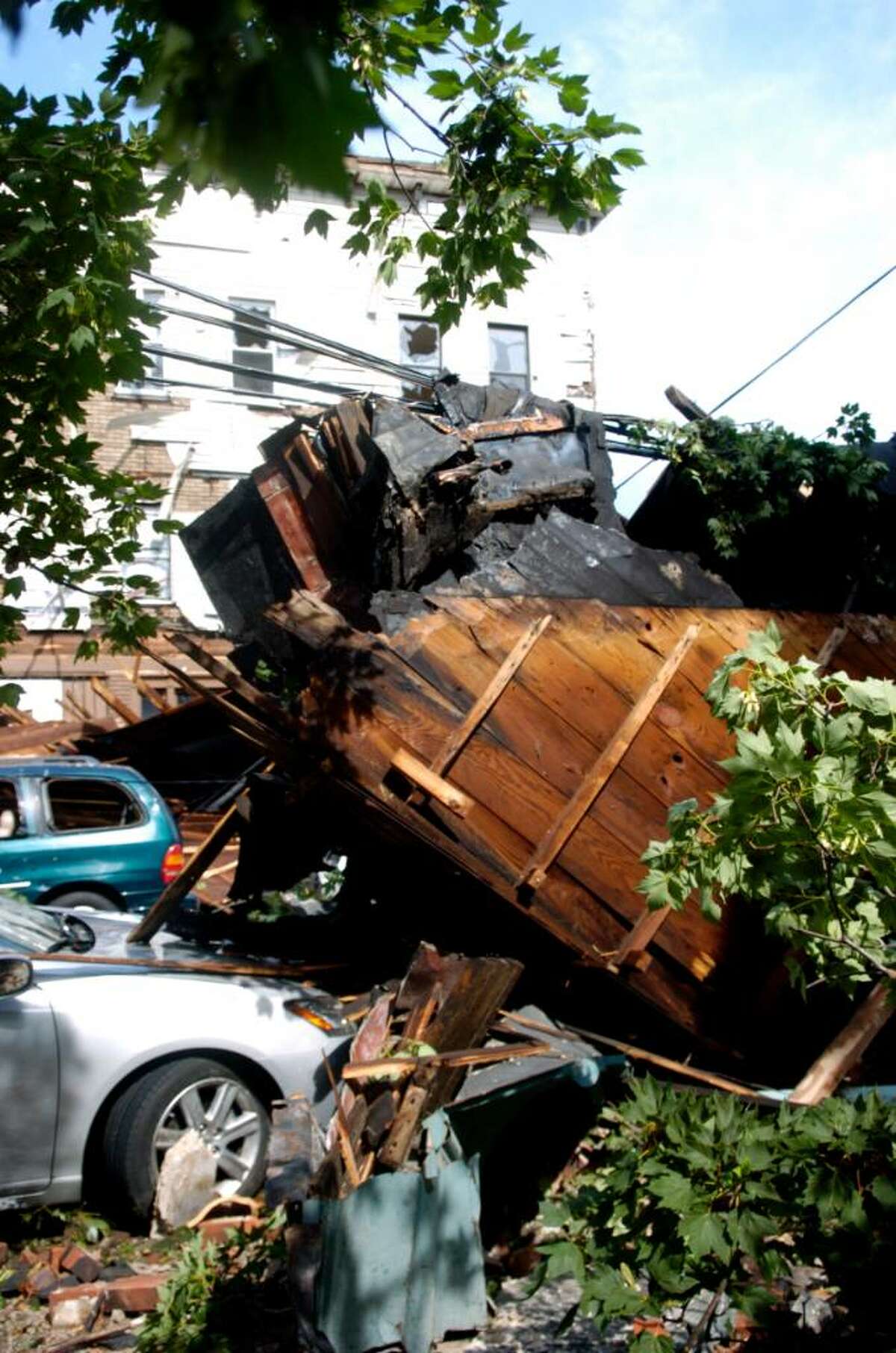Pieces of the facade of a building on East Main Street in Bridgeport lay across cars and power lines after a storm tore through the area Thursday, June 24, 2010.