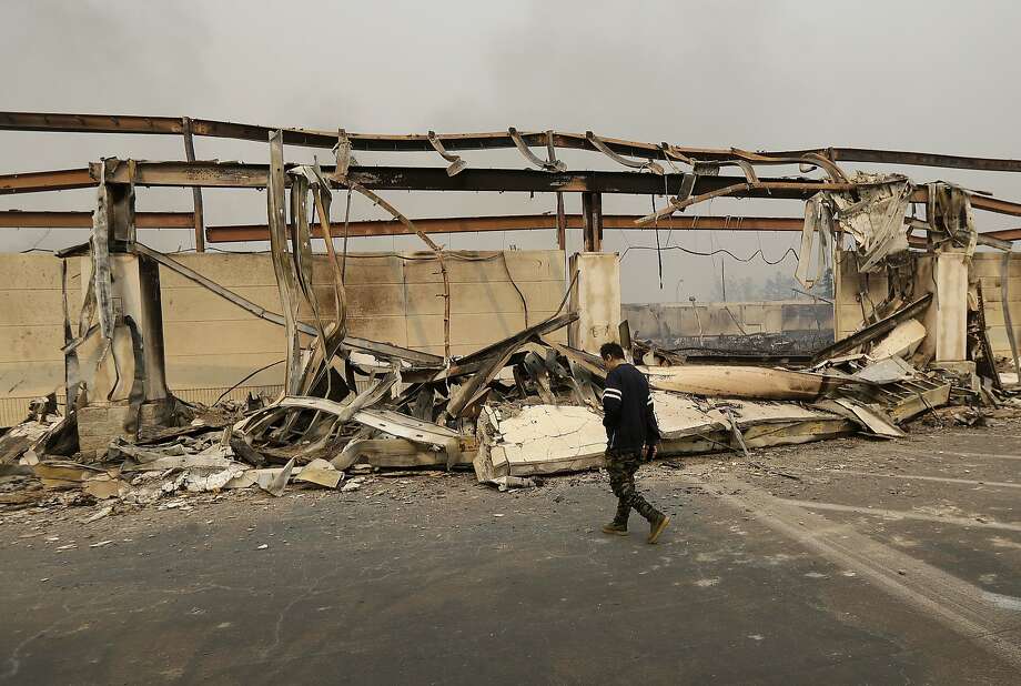 A man walks past the front of a Kmart store destroyed by a fire in Santa Rosa, Calif., Monday, Oct. 9, 2017. Wildfires whipped by powerful winds swept through Northern California in October 2017, sending residents on a headlong flight to safety through smoke and flames as homes burned. Photo: Jeff Chiu, Associated Press
