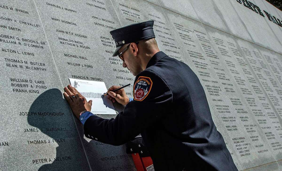 A New York City firefighter makes a rubbing of a name of a loved one on the memorial after the formal proceedings at the 20th Annual New York State Fallen Firefighters Memorial ceremony at the Convention Center at the Empire State Plaza on Tuesday, Oct. 10, 2017, in Albany, N.Y. (Skip Dickstein/Times Union)