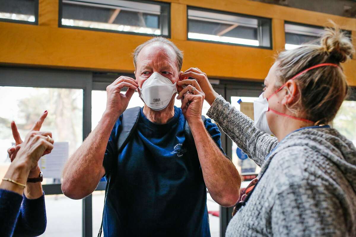 Kristin Jellison (right) helps Mike Jellison secure a mask at the Red Cross evacuation center at the Finley Community Center in Santa Rosa, Calif., on Tuesday, Oct. 10, 2017. Fires ravaged the area and forced residents to evacuate their homes. People are wearing masks to protect themselves from thick smoke outside.