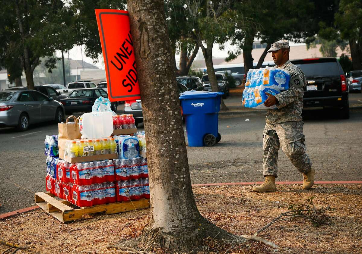 Seargeant Narayan Aman (right) of the 870th Military Police Company carries a donation of water outside the Petaluma Community Center while supplying aid for the fires that tore through Napa and Santa Rosa in Petaluma, Calif., on Tuesday, Oct. 10, 2017.