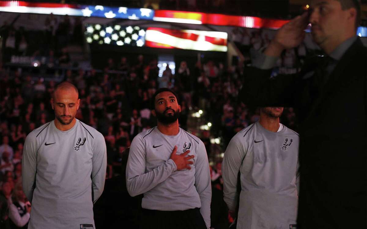 Spurs' Darrun Hilliard (center) holds his hand to his heart while teammate Manu Ginobili (left) bows his head during the U.S. national anthem before their pre-season game against the Orlando Magic at the AT&T Center on Tuesday, Oct. 10, 2017. (Kin Man Hui/San Antonio Express-News)