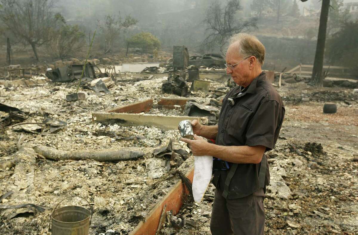 Chuck Rippey looks over a cup found in the burned out remains of his parent's home at the Silverado Resort, Tuesday, Oct. 10, 2017, in Napa, Calif. Charles Rippey, 100 and his wife Sara, 98, died when wind whipped flames swept through the area Sunday night. (AP Photo/Rich Pedroncelli)