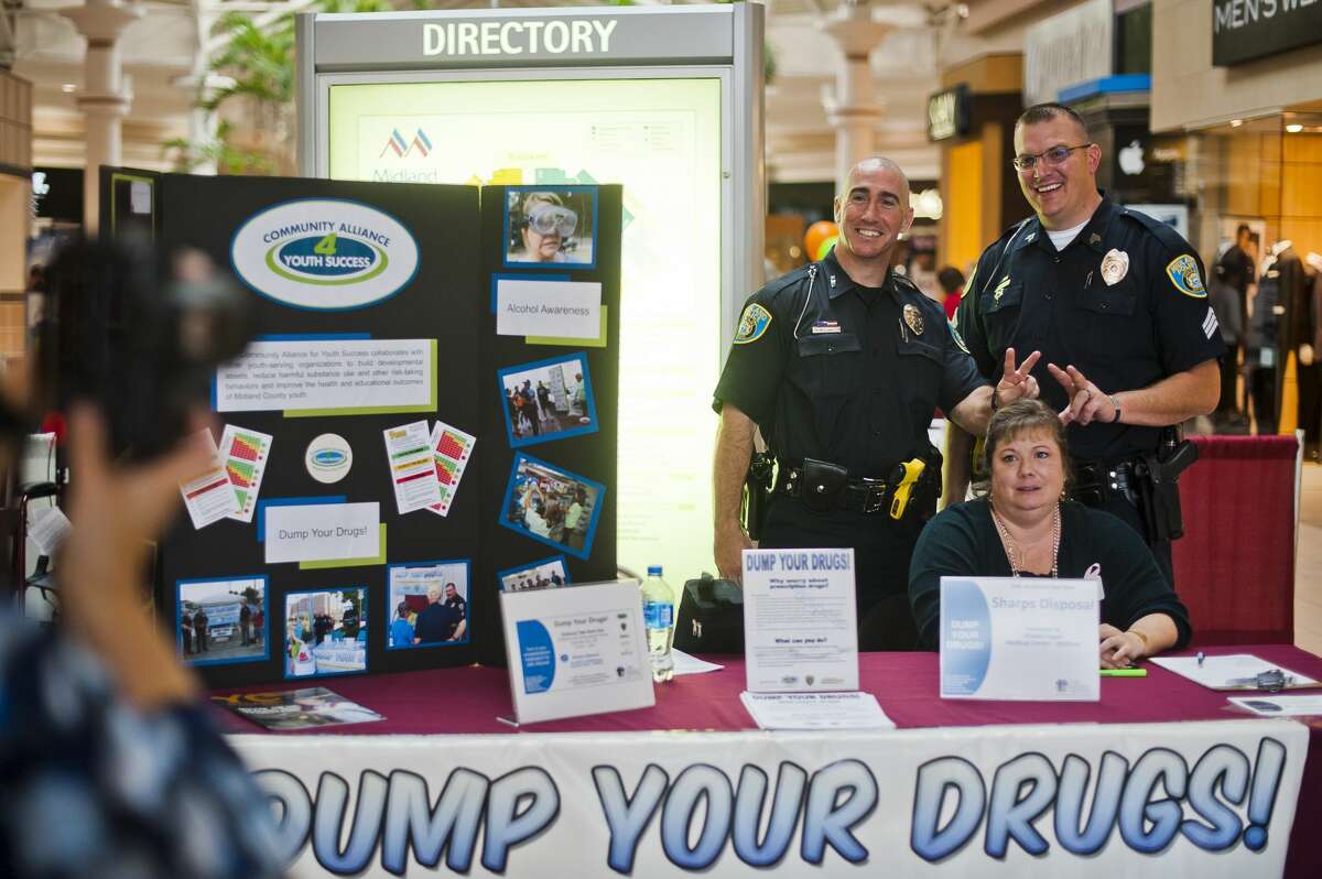 Midland Police Community Relations Officer Paul McDonald, left, and Sgt. Chris Wenzell, right, stick up bunny ears behind Michelle Beeck, a prevention specialist with the Legacy Center, as Barb Swierzbin, a prevention services coordinator with the Legacy Center, left, takes a photo during a "Dump Your Drugs" event on Wednesday at the Midland Mall. The event allows people to drop off their expired and unwanted prescriptions and also serves to promote the 24-hour secure drop box located at the Law Enforcement Center. (Katy Kildee/kkildee@mdn.net)