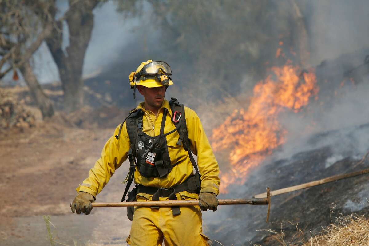 A firefighter works to control a fire near a bulldozer line created behind homes along Bennett Valley Road as he and other firefighters monitor it 's progress on Wednesday, October 11, 2017 in Santa Rosa, Calif.