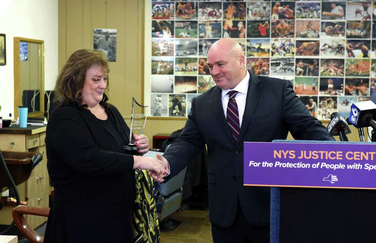 Theresa Hastings, owner of Niskayuna Barbershop, is presented with a New York State Justice Center for the Protection of People with Special Needs Champion Award by Ed O'Leary, Justice Center assistant chief on Thursday, Oct. 12, 2017, in Niskayuna, N.Y. Hastings reported the abuse of a person with special needs, which she witnessed at her shop. (Will Waldron/Times Union)