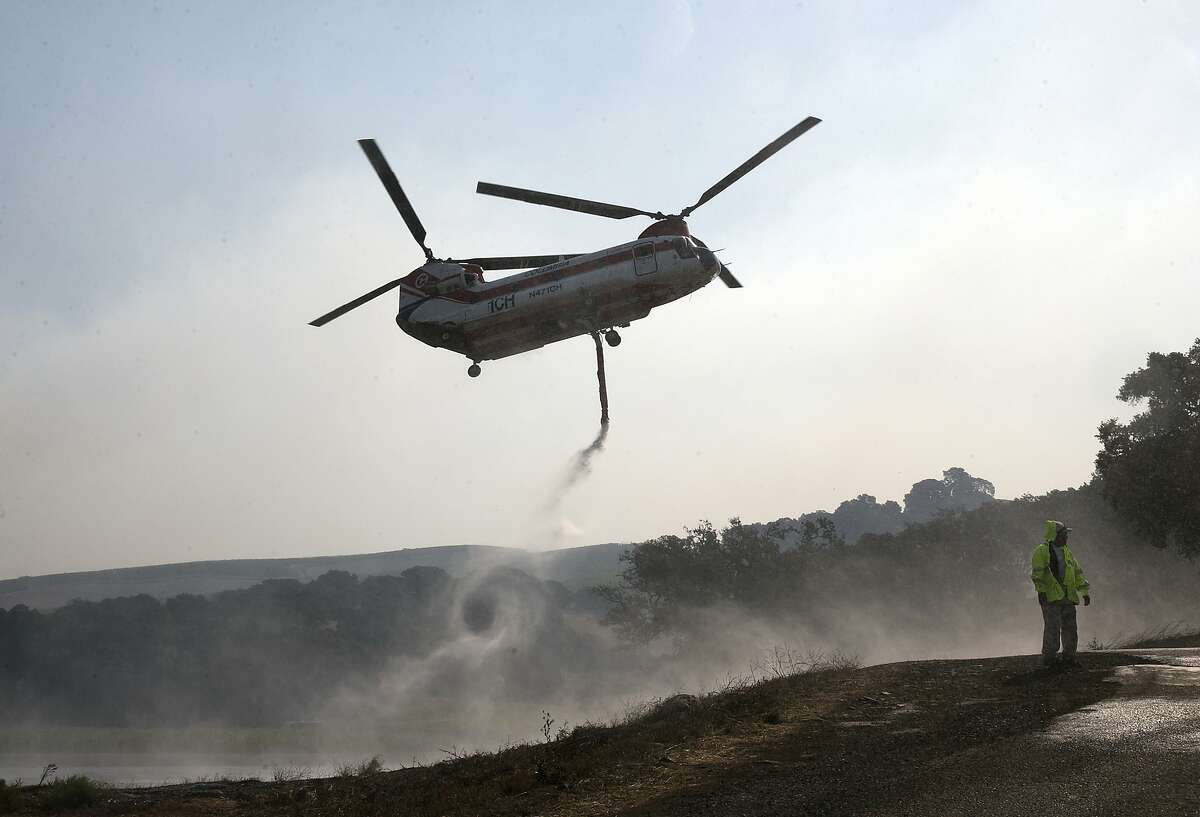 A helicopter draws water from a pond to help put out a fire near Napa, Calif., on Thursday, Oct. 12, 2017. Gusting winds and dry air forecast for Thursday could drive the next wave of devastating wildfires. (AP Photo/Rich Pedroncelli)