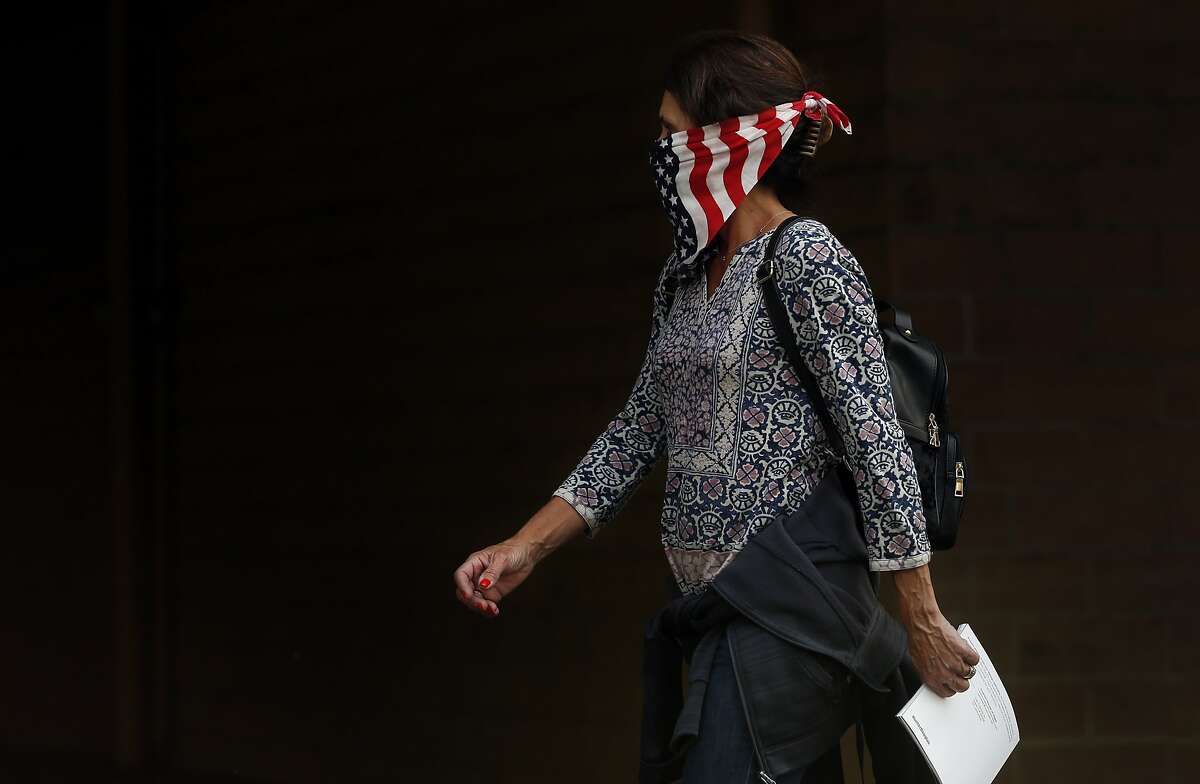 A woman walks past a store wearing a bandana as a mask to protect herself from the smoke Oct. 9, 2017 in Napa, Calif. A fire tore through the area on the evening of Oct. 8, destroying properties and vineyards.