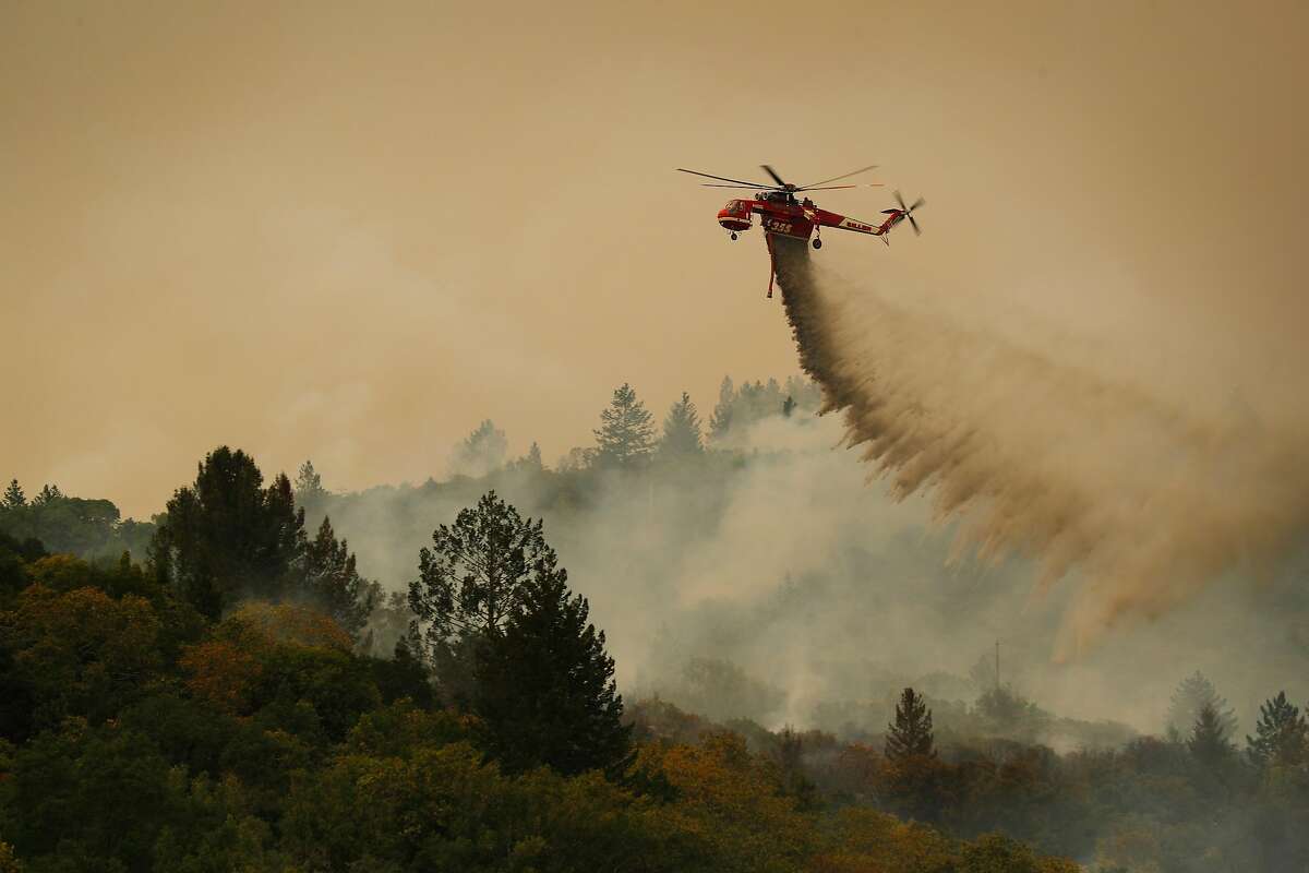 A Cal Fire helicopter drops water on a smoldering area as the Partrick Fire continue to burn slowly east of Sonoma, Calif., on Thursday, October 12, 2017. The Napa and Sonoma valleys continue to be under threat from several fires not yet under control and growing fears that strong winds might worsen the situation.