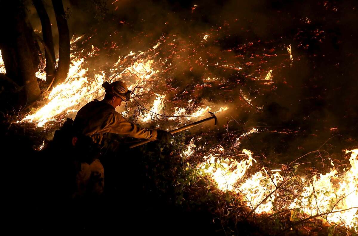 A CalFire firefighter uses a hand tool as he monitors a firing operation while battling the Tubbs Fire on October 12, 2017 near Calistoga, California. At least thirty one people have died in wildfires that have burned tens of thousands of acres and destroyed over 3,500 homes and businesses in several Northern California counties. (Photo by Justin Sullivan/Getty Images)