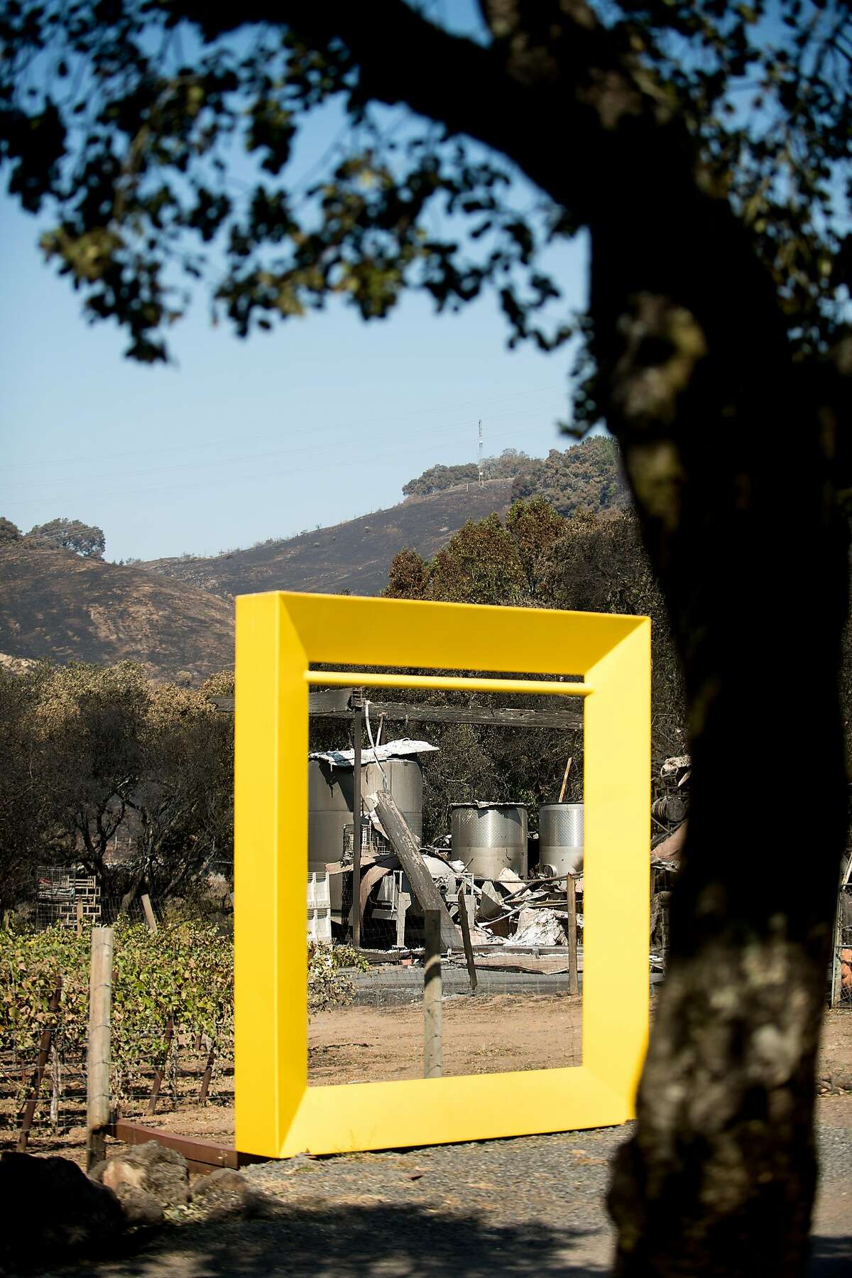 Wine tanks burned by the Tubbs fire stand behind Robert Ellison's sculpture 