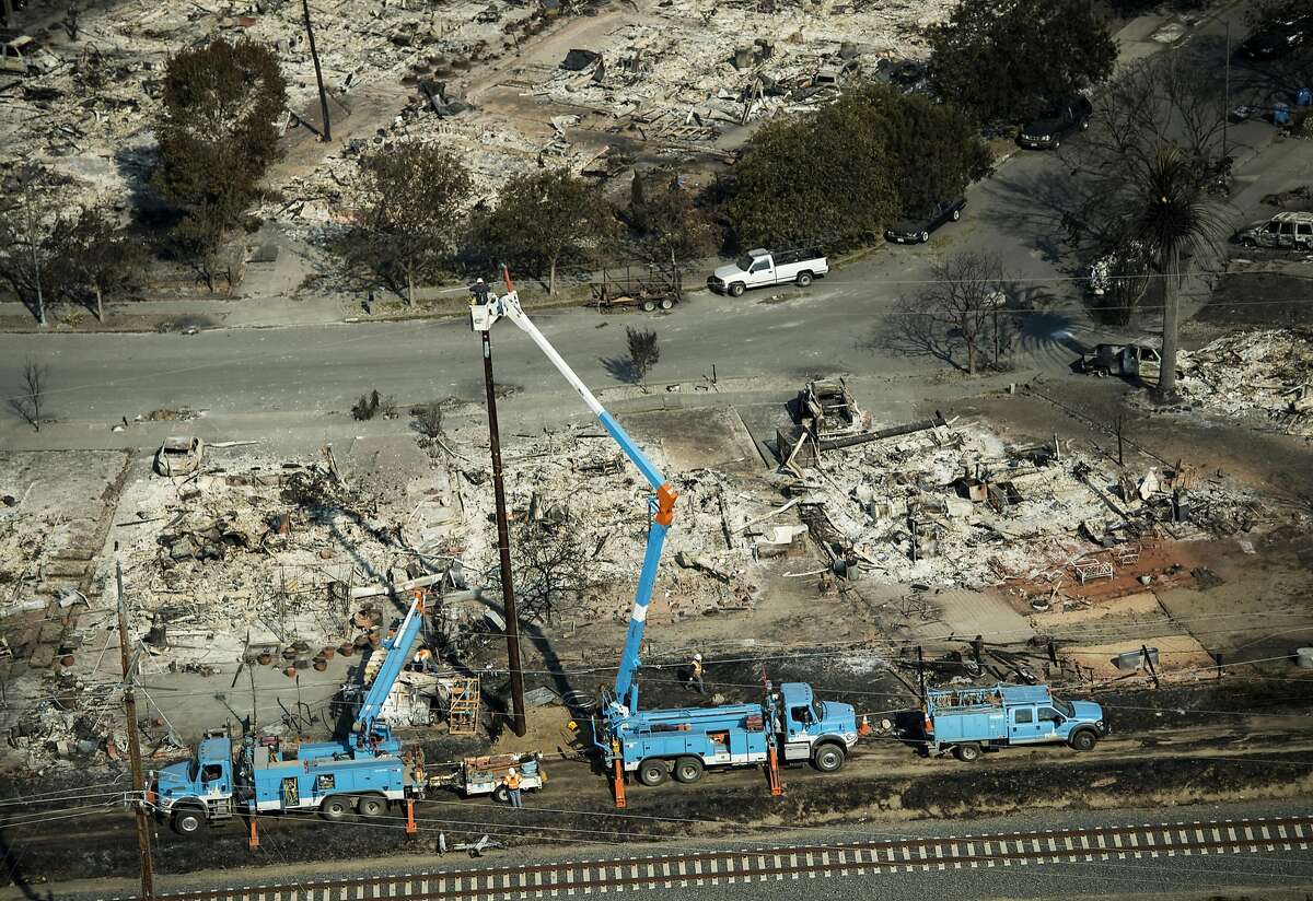 Pacific Gas & Electric Co. (PG&E) employees work to fix downed power lines burned by wildfires in this aerial photograph taken above Santa Rosa, California, U.S., on Thursday, Oct. 12, 2017. Wildfires that tore through northern California's iconic wine-growing regions have prompted evacuations of more than 20,000 people, killed 11 and damaged some of the most valuable vineyards and wineries in the U.S. About 1,500 commercial, residential and industrial structures were burned, and damage assessment teams have started accounting for the destruction. Photographer: David Paul Morris/Bloomberg