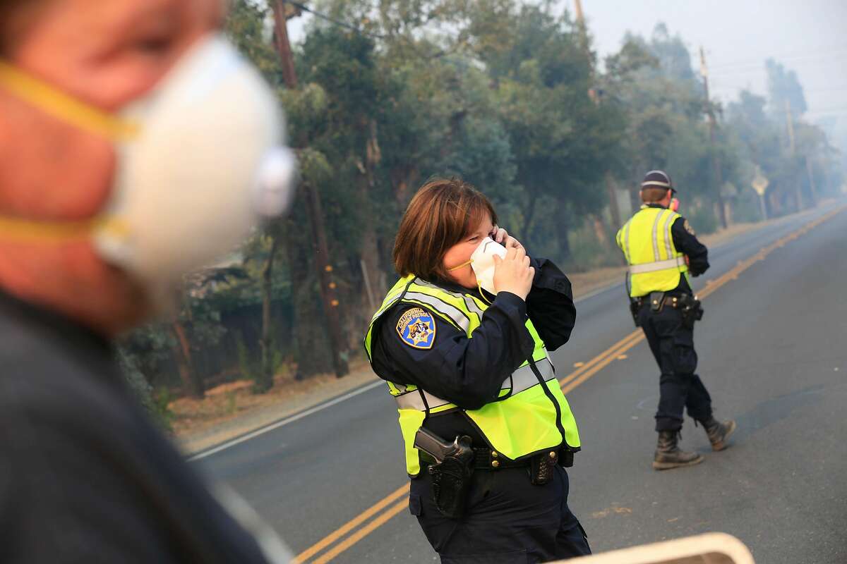 California Highway Patrol officer Tracy Ross (center) talks on the phone while assiting Tom Sours (left) of Napa, as he was trying to get to his home to pick up some items on Friday, October 13, 2017 in Napa, Calif.