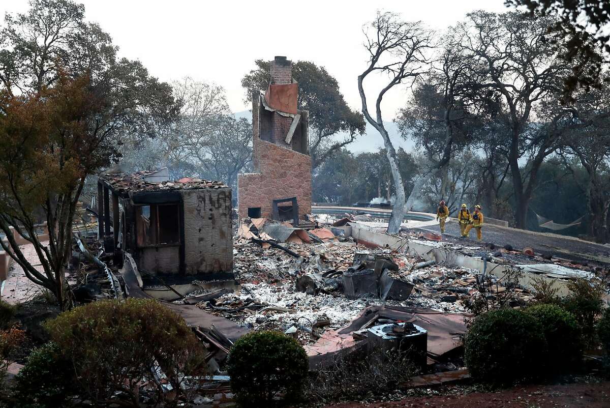 Three firefighters look at a large home that burned in The Ranch subdivision in Sonoma, Calif., on Saturday, October 14, 2017.