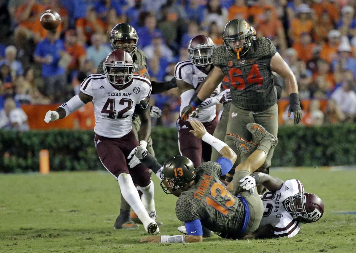Florida quarterback Feleipe Franks (13) flips a pass to a receiver just as he is hit by Texas A&M defensive lineman Zaycoven Henderson, bottom right, during the first half of an NCAA college football game, Saturday, Oct. 14, 2017, in Gainesville, Fla. (AP Photo/John Raoux)