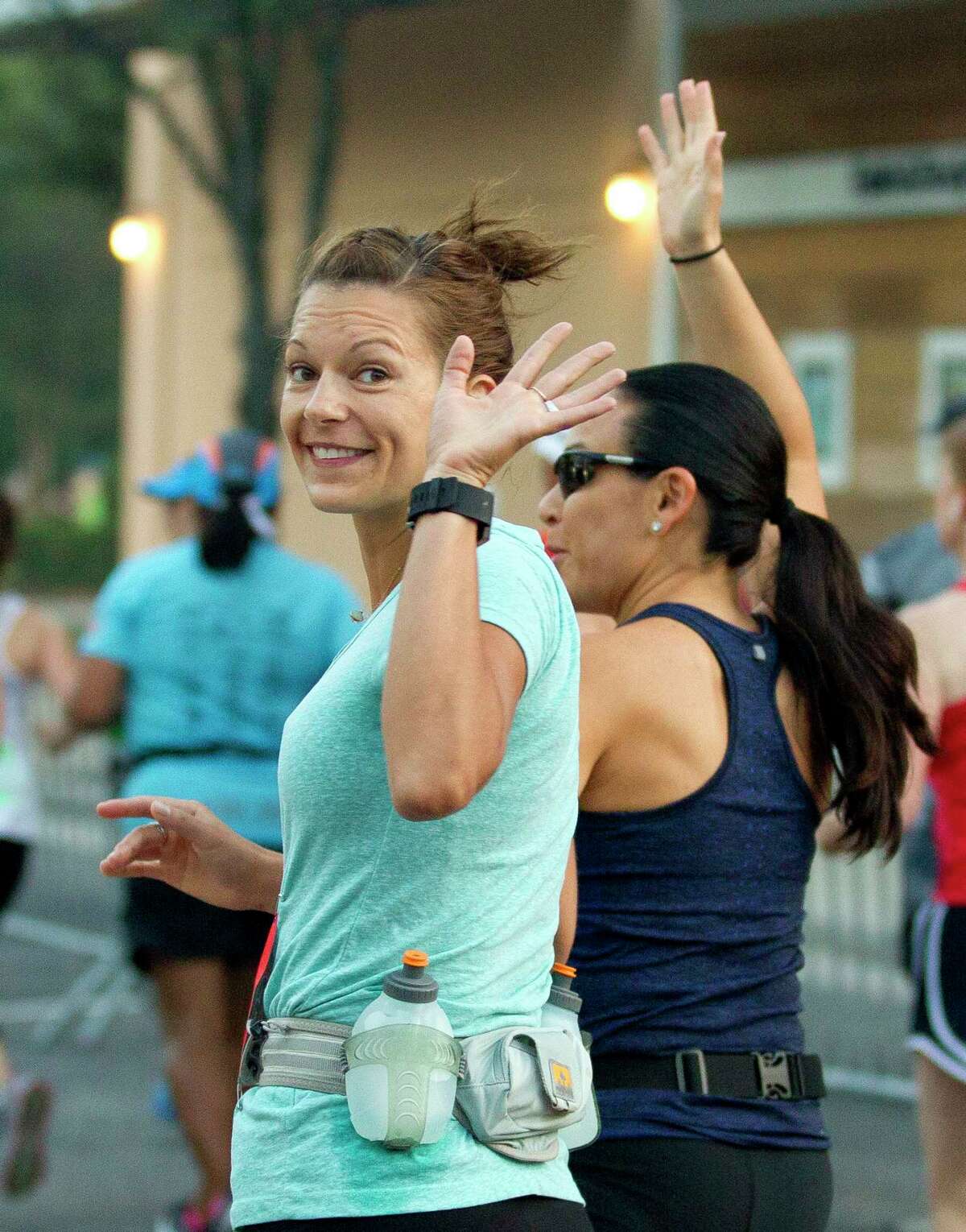 A woman waves as she takes part in the annual 10 for Texas race at Market Street, Saturday, Oct. 14, 2017, in The Woodlands.