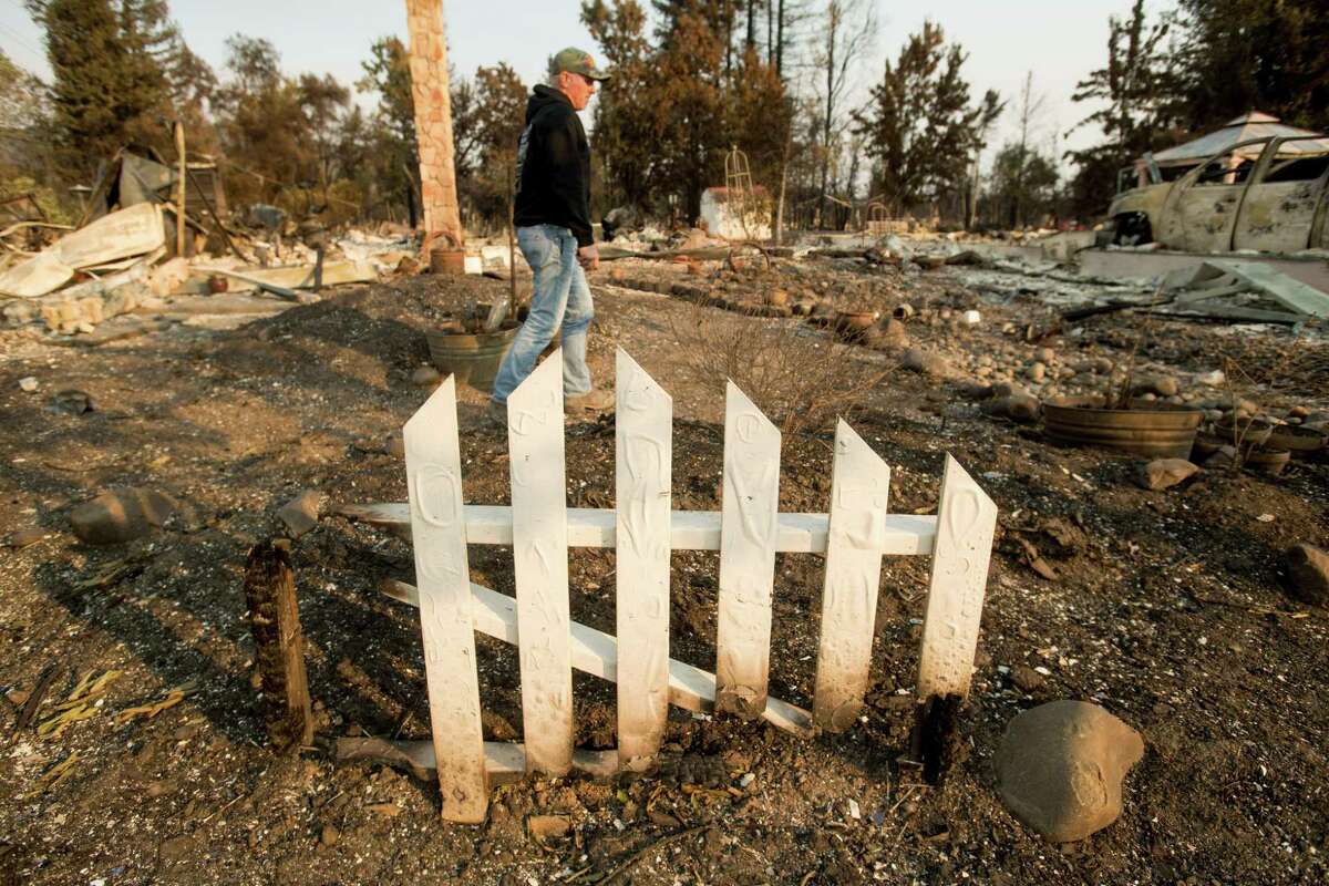 Santa Rosa firefighter Tony Niel passes a portion of fence standing at his Mark West Estates home, which burned during the Tubbs fire, on Thursday, Oct. 12, 2017, in Santa Rosa.