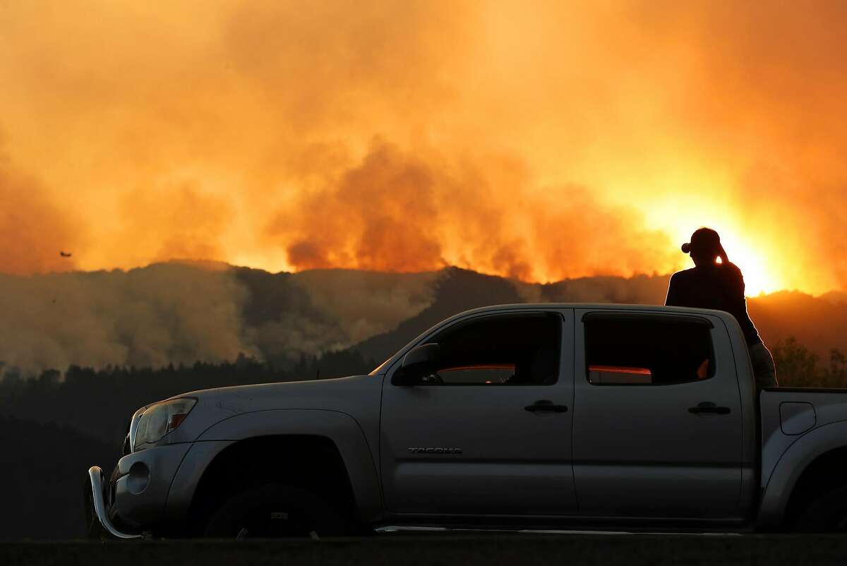 From atop his truck parked along Highway 29, Marcos Barrera of Napa watches fires burn west of St. Helena, Calif., on Sunday, October 15, 2017.