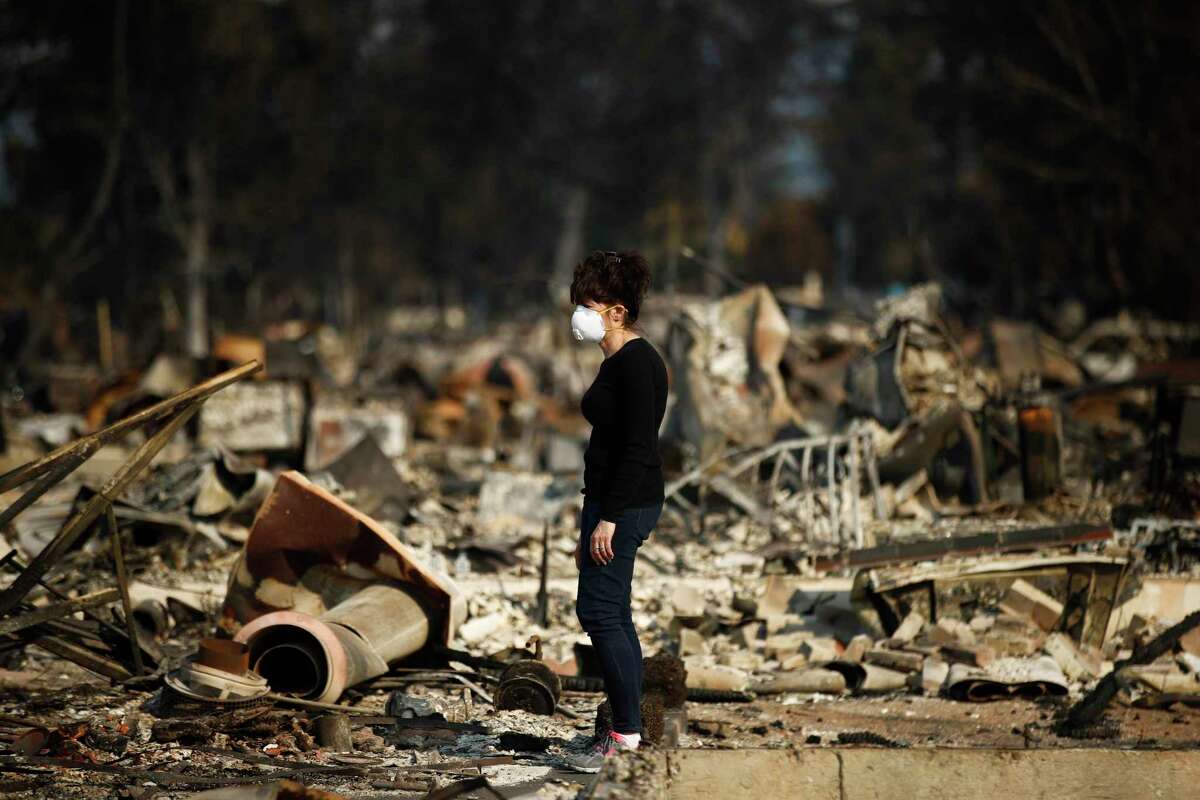 Karen Curzon stands in what remains of her home, which was destroyed by a wildfire in the Coffey Park neighborhood, Sunday, Oct. 15, 2017, in Santa Rosa, Calif. "We are going to rebound, rebuild and get this community back," said Curzon.