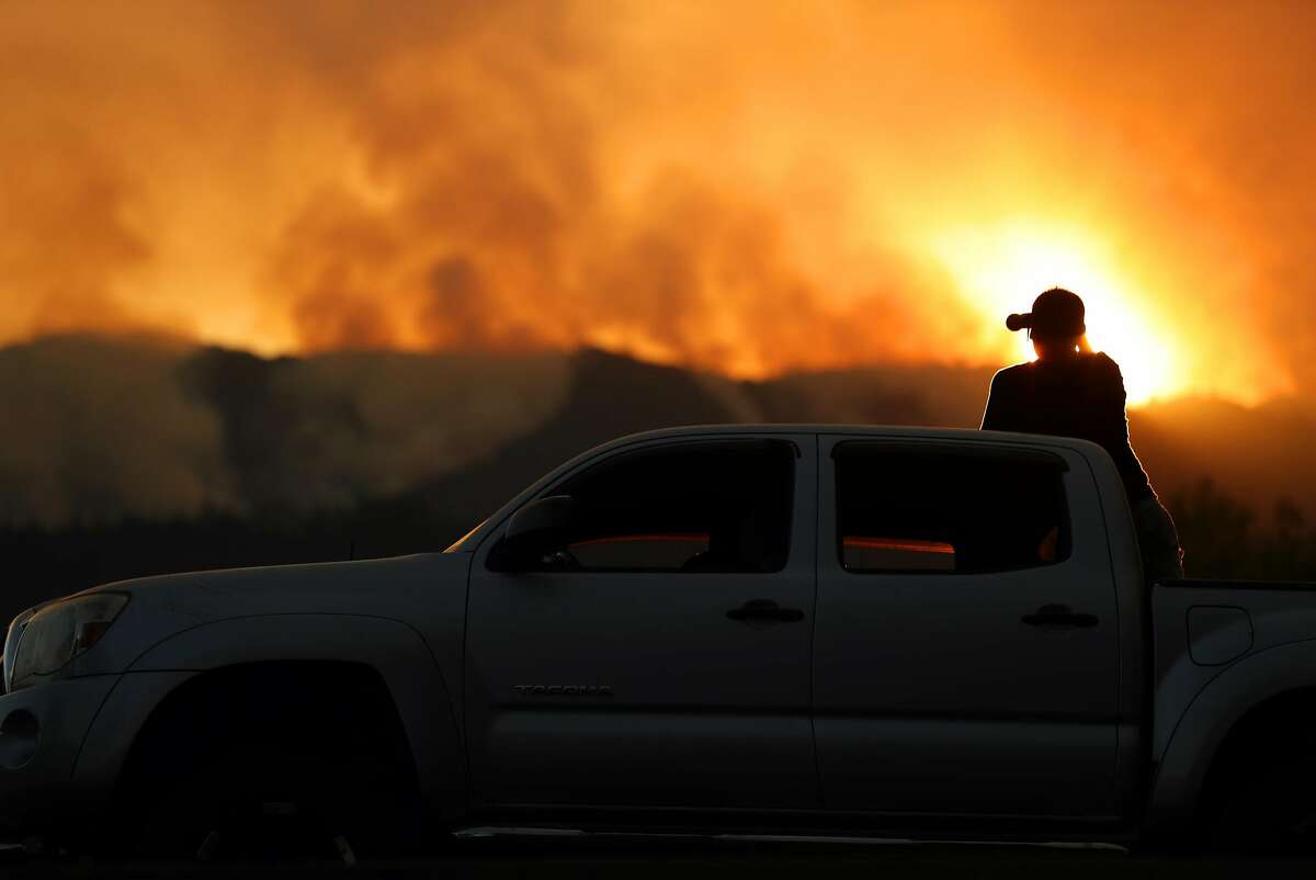 From atop his truck parked along Highway 29, Marcos Barrera of Napa watches fires burn west of St. Helena, Calif., on Sunday, October 15, 2017.
