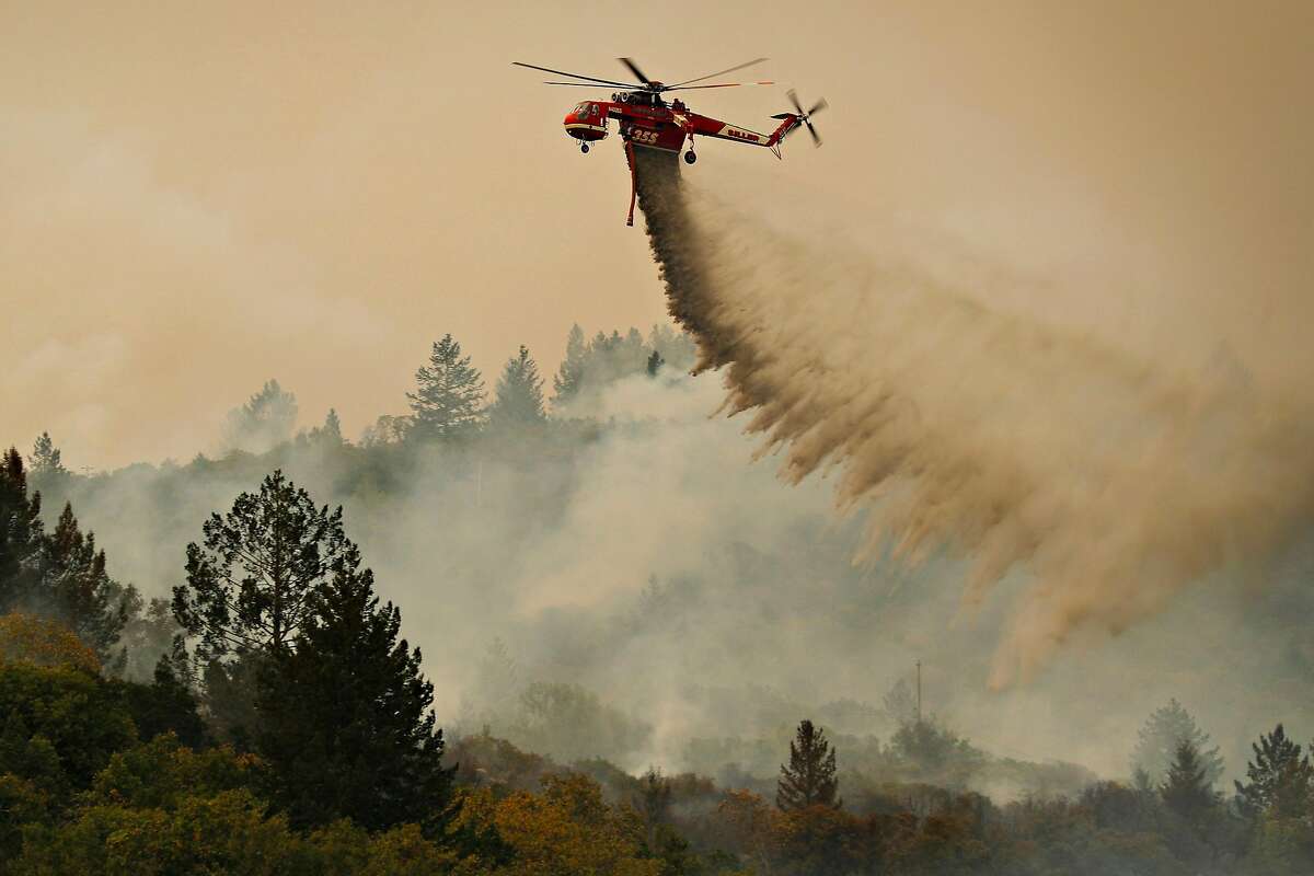 A Cal Fire helicopter drops water on a smoldering area as the Partrick Fire continue to burn slowly east of Sonoma, Calif., on Thursday, October 12, 2017. The Napa and Sonoma valleys continue to be under threat from several fires not yet under control and growing fears that strong winds might worsen the situation.