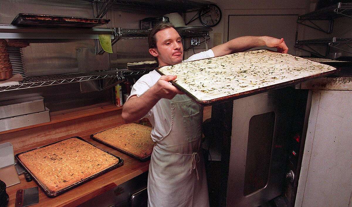 FILE-- Chris Miller of L'Osteria Del Forno in the North Beach area lifts a focaccia tray from the oven top to the oven. Behind him are freshly baked focaccia.
