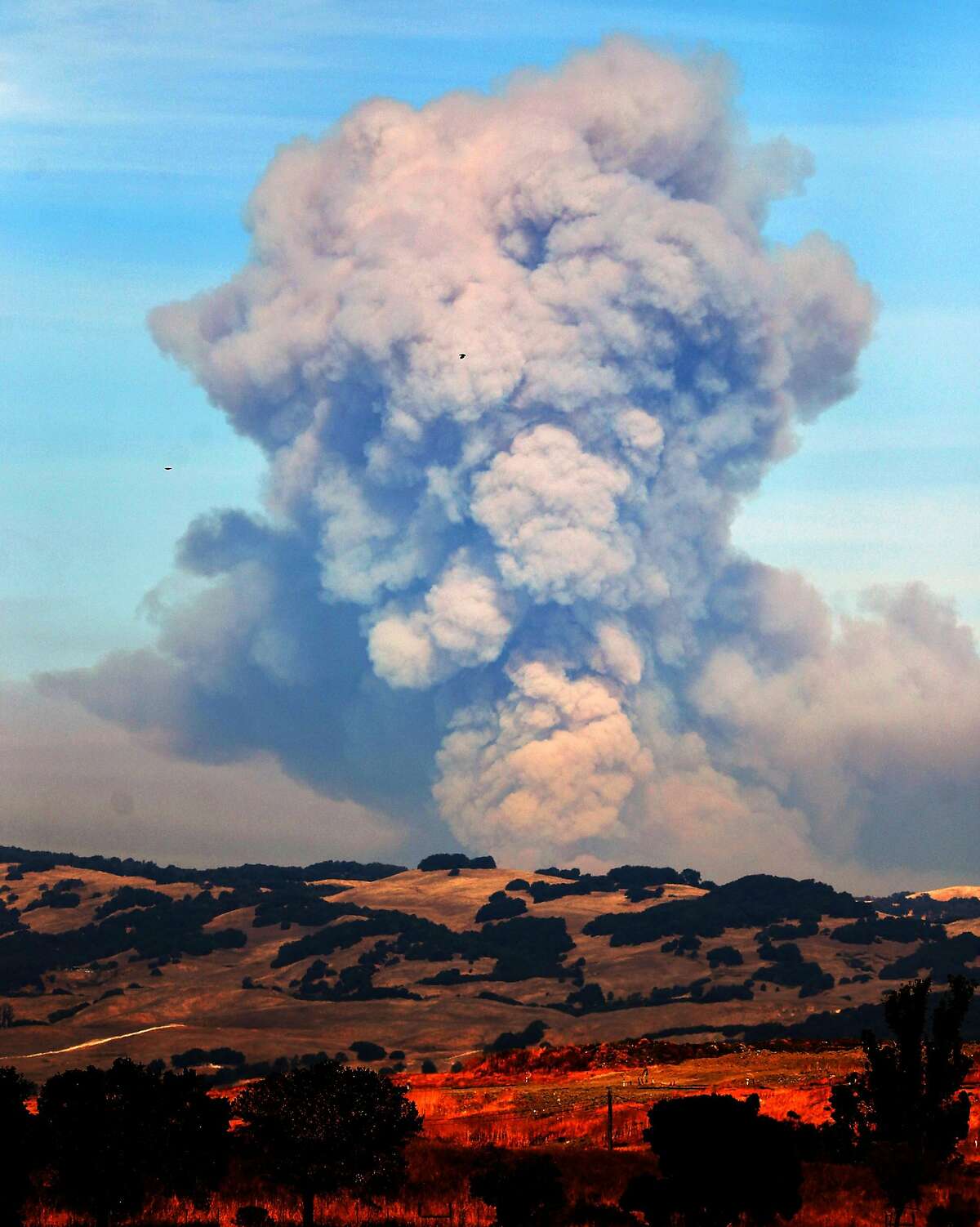 A large plume of smoke rises above the mountains between Napa and Sonoma, Calif., on Sunday, October 15, 2017.