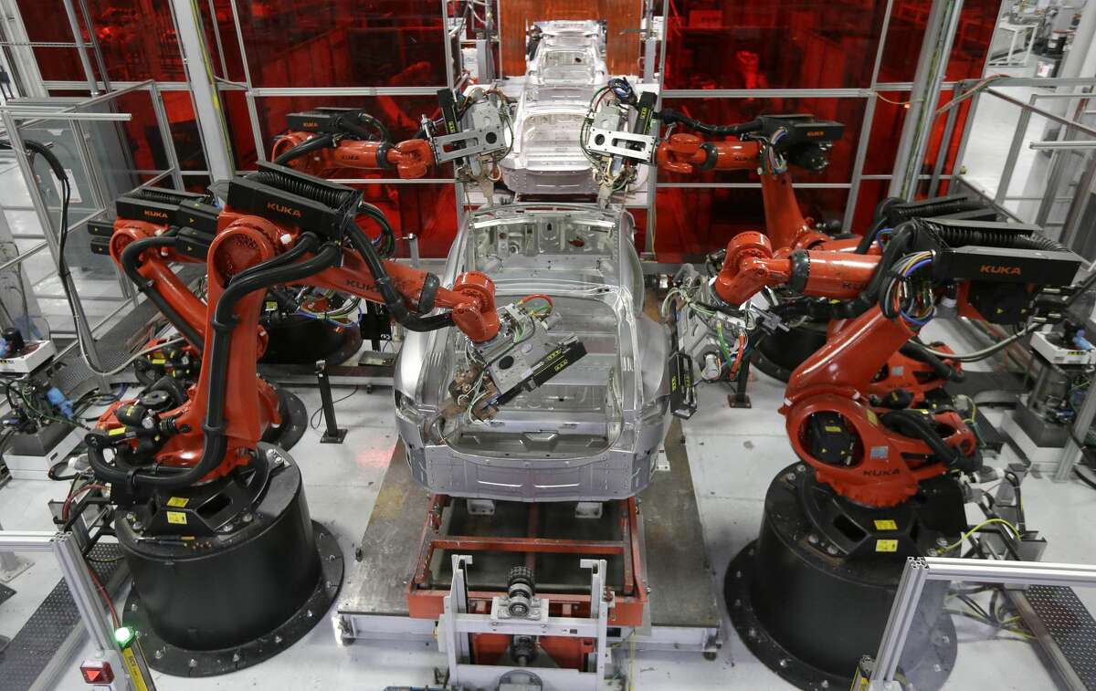 Kuka robots work on Tesla Model S cars in the Tesla factory in Fremont, Calif., Thursday, May 14, 2015. (AP Photo/Jeff Chiu)