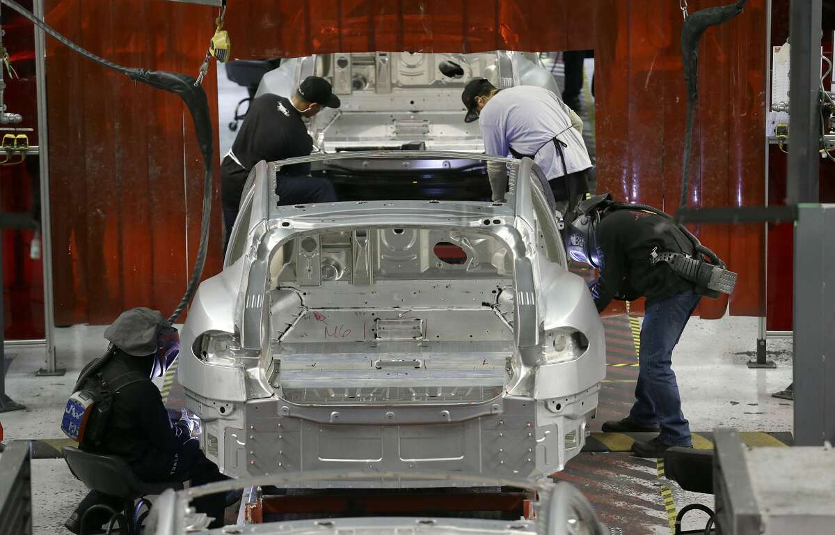 Tesla employees work on a Model S cars in the Tesla factory in Fremont, Calif., Thursday, May 14, 2015. (AP Photo/Jeff Chiu)