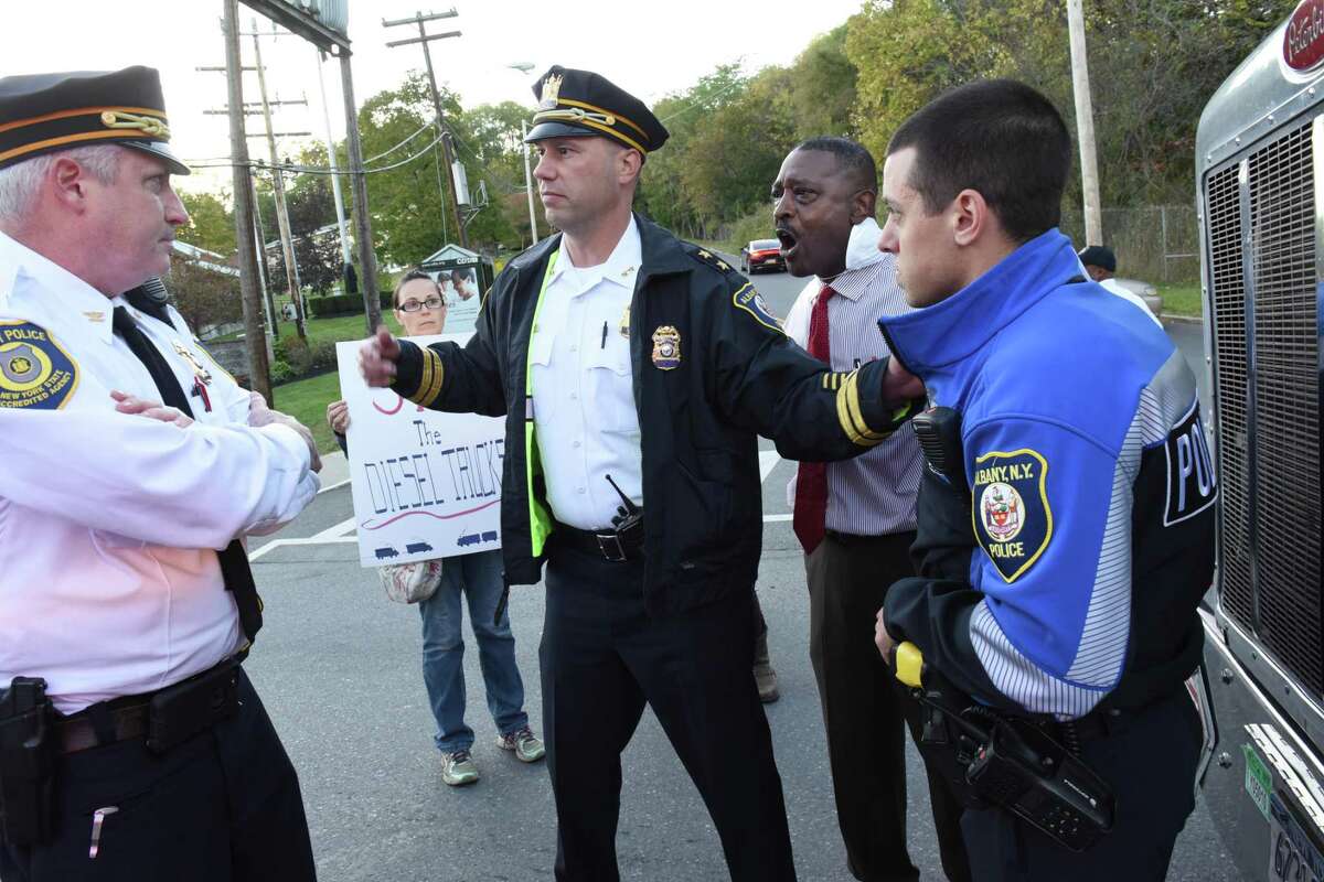 Police talk to Willie White, executive director of AVillage, second from right, as he stands in the middle of South Pearl St. and blocks a diesel truck from driving by the Ezra Prentiss homes on Tuesday, Oct 17, 2017 in Albany, N.Y. People were protesting diesel trucks polluting the air as they drove past the homes and want them to be re-routed. (Lori Van Buren / Times Union)