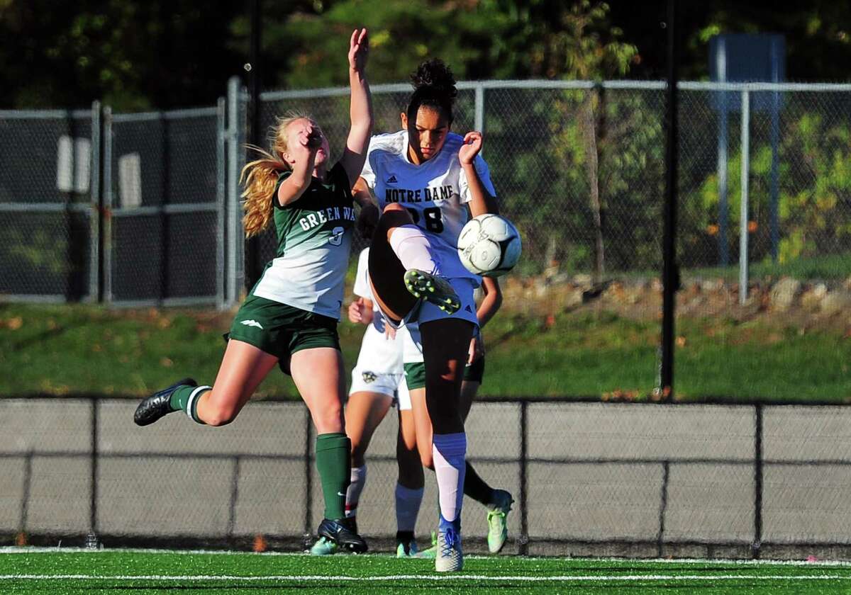 Notre Dame of Fairfield's Jazmine Fred high kicks the ball as New Milford's Sarah Marsan intercepts during girls soccer action in Fairfield, Conn., on Tuesday Oct. 17, 2017.