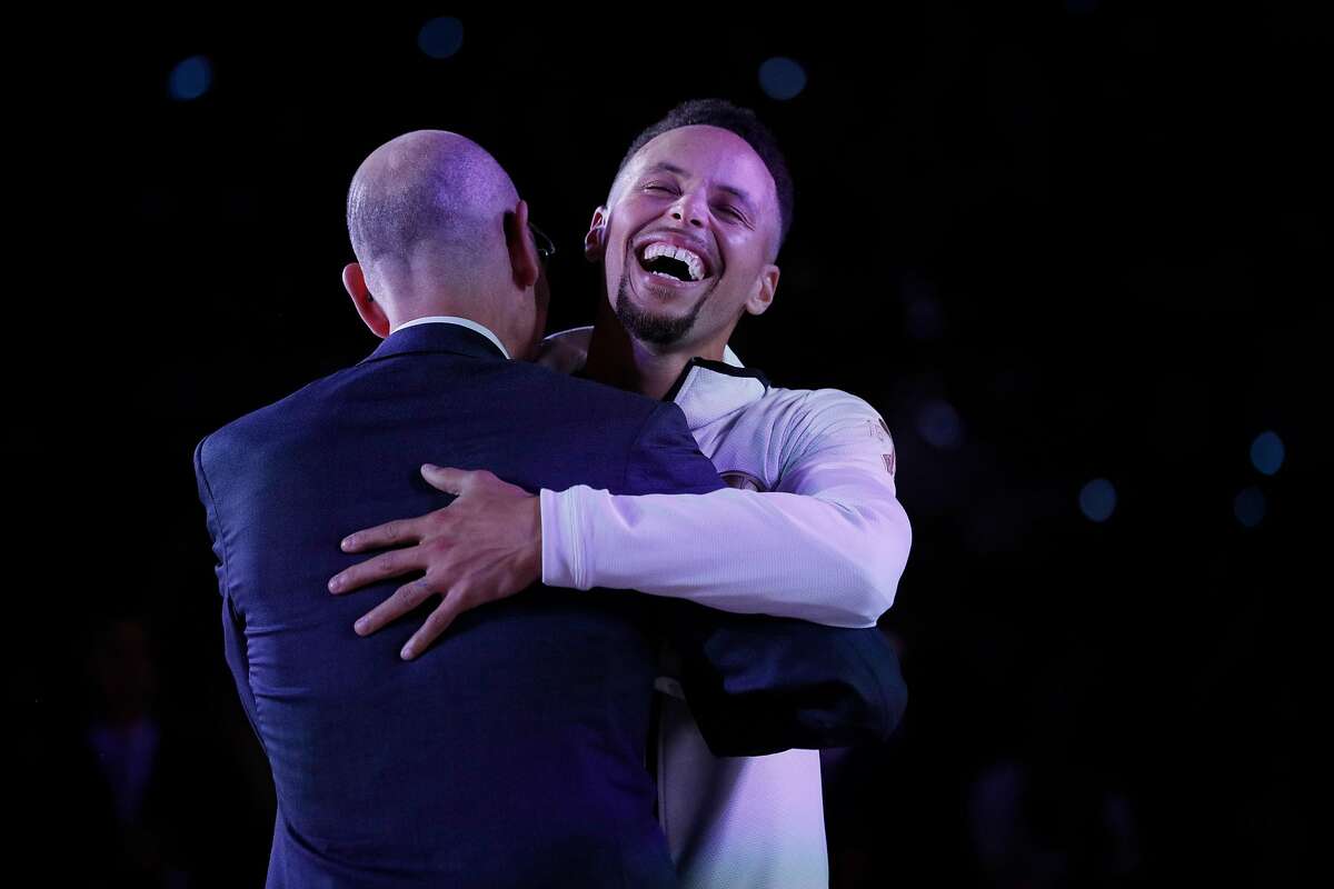Stephen Curry (30) hugs NBA Commissioner Adam Silver on his way to get his championship ring before the Golden State Warriors played the Houston Rockets at Oracle Arena in Oakland, Calif., Tuesday, October 17, 2017.