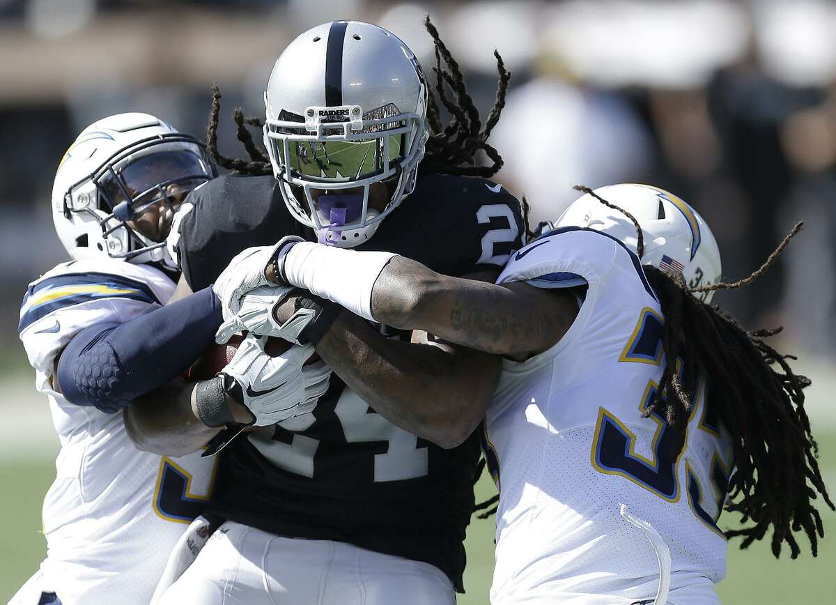 Marshawn Lynch struggles for yardage Sunday against the Chargers’ Adrian Phillips (left) and Tre Boston. After a strong start in the game, Lynch had just five touches, and 14 yards, in the second half.