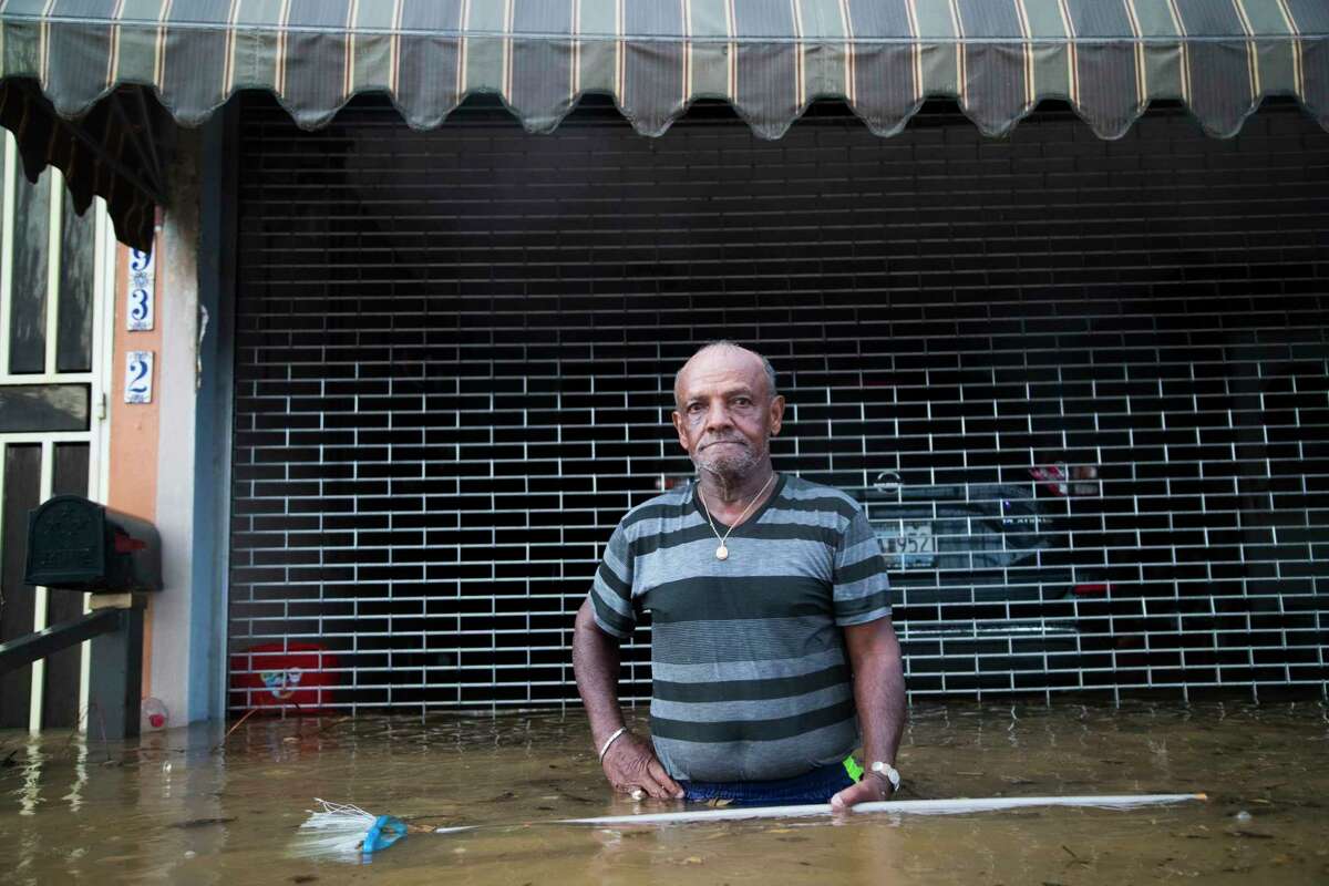 Maximiliano Encarnacion a resident of San Juan, Puerto Rico, holds a broom he used to push away debris carried by the flood waters caused by a torrential rains, Sunday, Oct. 8, 2017, in San Juan, 18 days after Hurricane Maria touchdown in Puerto Rico. Almost a month after the hurricane, the island of Puerto Rico is still struggling to clear up the debris from the hurricane to avoid floods.