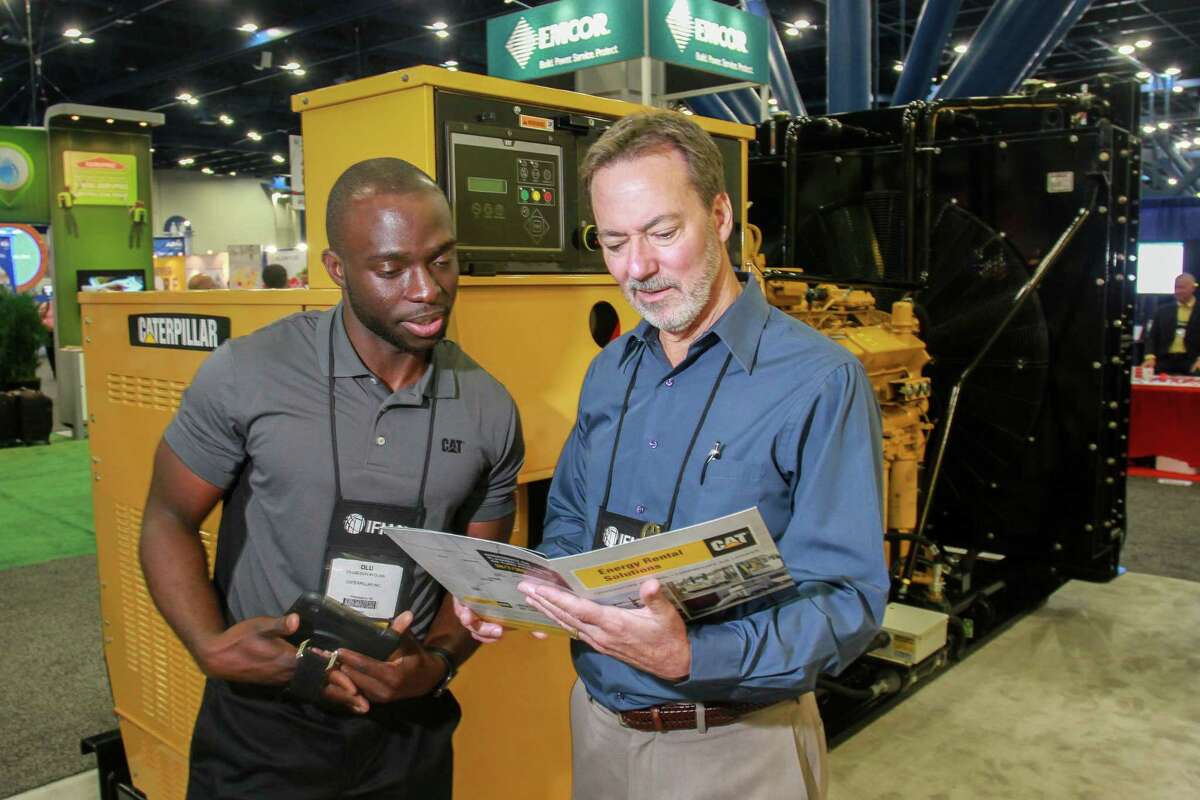 Olu Afolabi, left, of Caterpillar, showing a Caterpillar G3412 gas generator to Scott Foster of the Texas Department of Public Safety, at the International Facility Management Association's annual convention. The generator can provide both prime and standby power. (For the Chronicle/Gary Fountain, October 19, 2017)