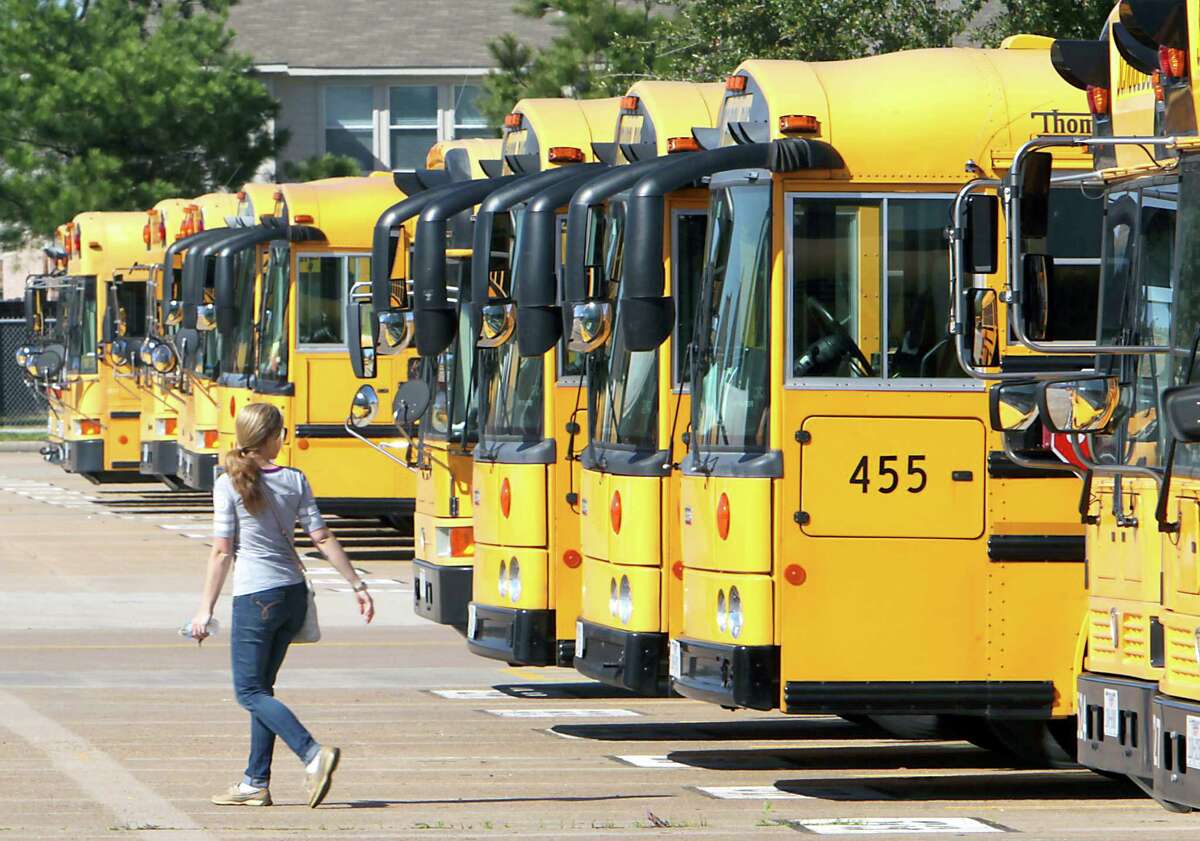 A school bus driver walks past a line of busses at a Katy Independent School District bus barn in 2014. ( James Nielsen / Houston Chronicle )