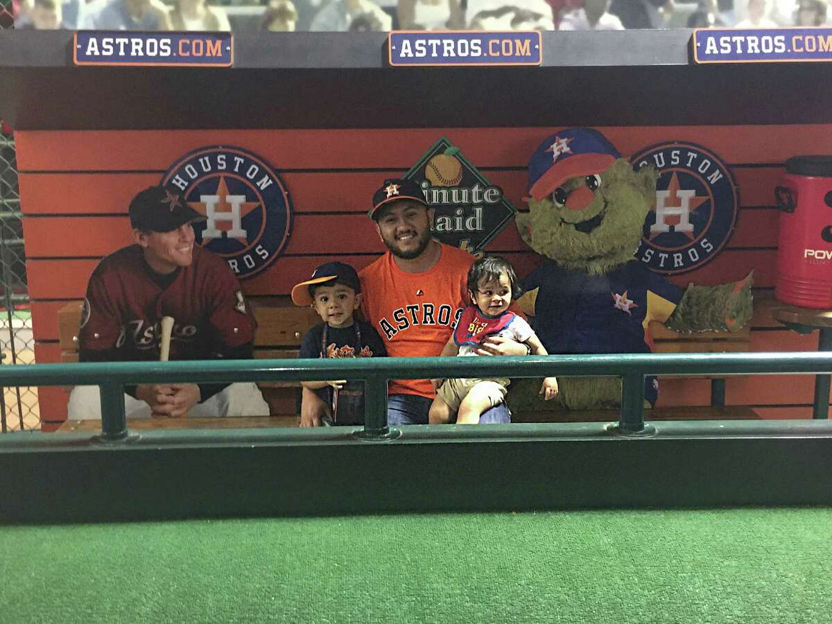 Flanked by cardboard cutouts of Astros great Craig Biggio and mascot Orbit, Victor Lombrana creates a memory with sons Leonardo, left, and Nicholas.