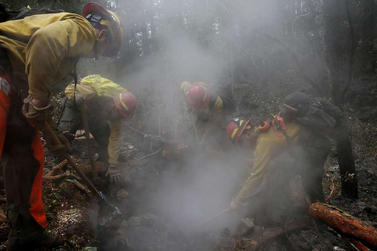 Firefighters from Eugene, Oregon, from left, Cameron McConnell, David Lopez-Parker, Skylar Lillingston and John Peterson work on mop up near Sugarloaf Ridge State Park Oct. 19, 2017 in Kenwood, Calif.