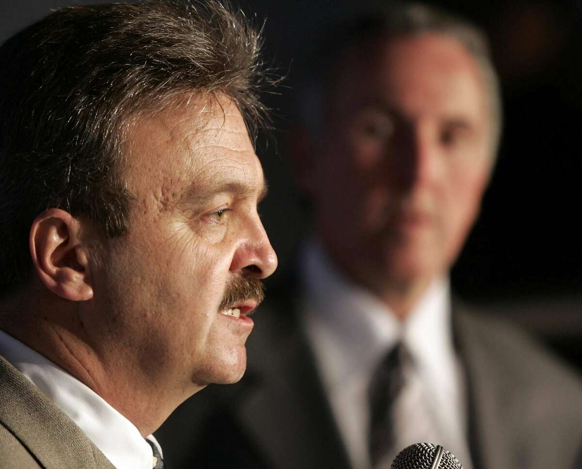 Dodgers general manager Ned Colletti listens at a question at his introduction press conference with owner Frank McCourt in the background at Dodger Stadium, Wednesday, November 16, 2005.